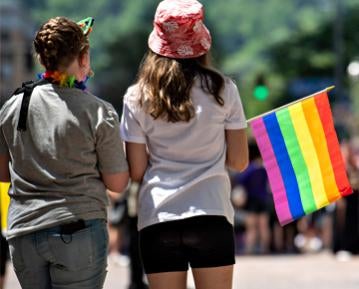 Two people carrying rainbow pride flag