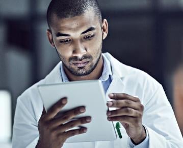 Student in white coat looking at iPad