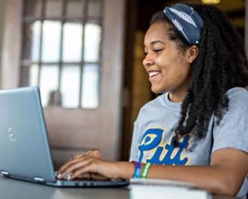 Student smiling typing on laptop