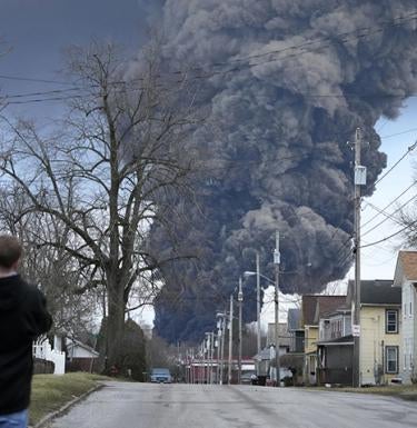 A man takes photos as a black plume rises over East Palestine, Ohio, as a result of a controlled detonation on Monday after a train derailment