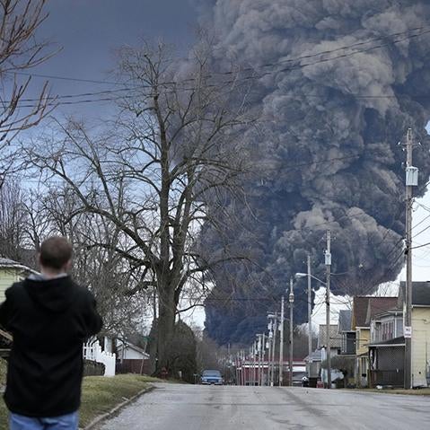 A man takes photos as a black plume rises over East Palestine, Ohio, as a result of a controlled detonation on Monday after a train derailment
